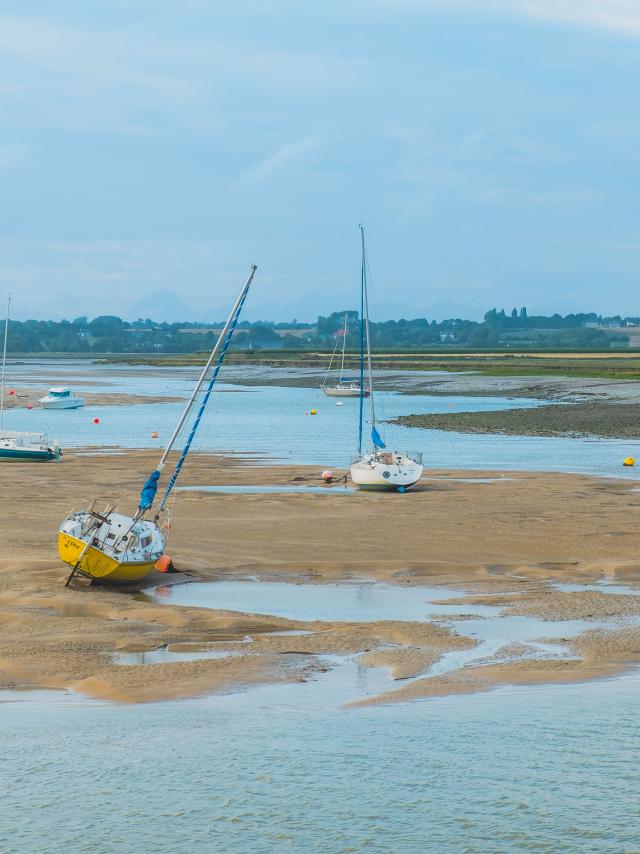 Several boats stranded on a muddy beach with shallow water