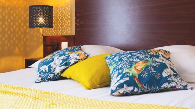 Lit avec des coussins colorés et une lampe de chevet