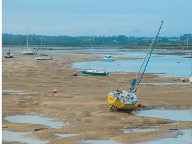 Boat beached on a shore with boats in the background