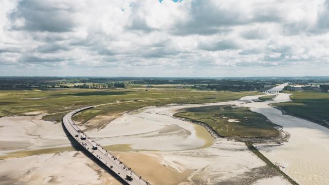 Wooden bridge over a sandy beach with people walking