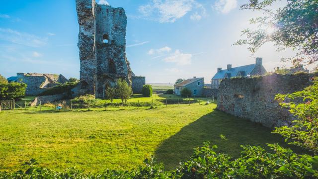 Ruines médiévales avec une tour en pierre et des bâtiments modernes