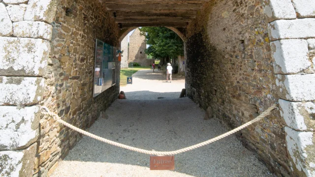 Stone archway passage with a window above and a sign on the ground