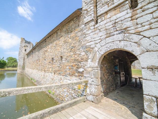 View of a section of an ancient stone castle with an arch and a wooden bridge leading to a door