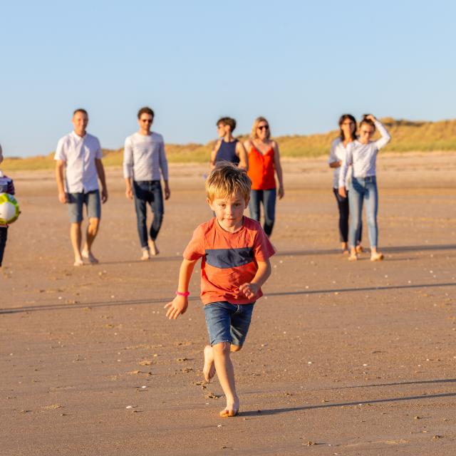 Un groupe d'enfants et d'adultes jouant avec un ballon sur une plage de sable