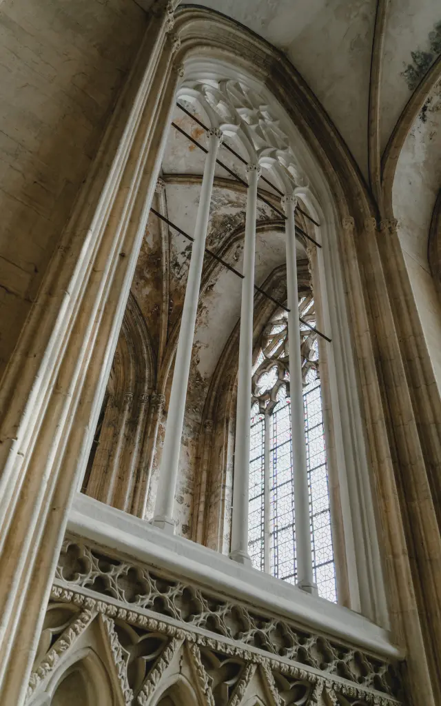 Vitrail gothique dans une cathédrale, avec des arcs et des colonnes en pierre
