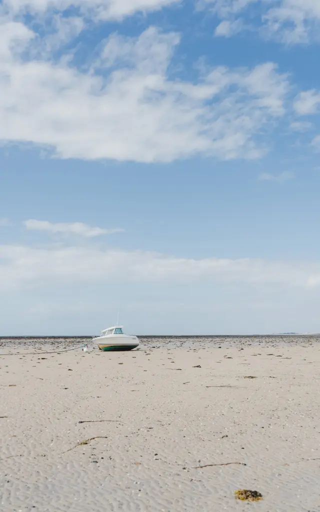 Ein kleines weißes Boot gestrandet auf einem feinen Sandstrand