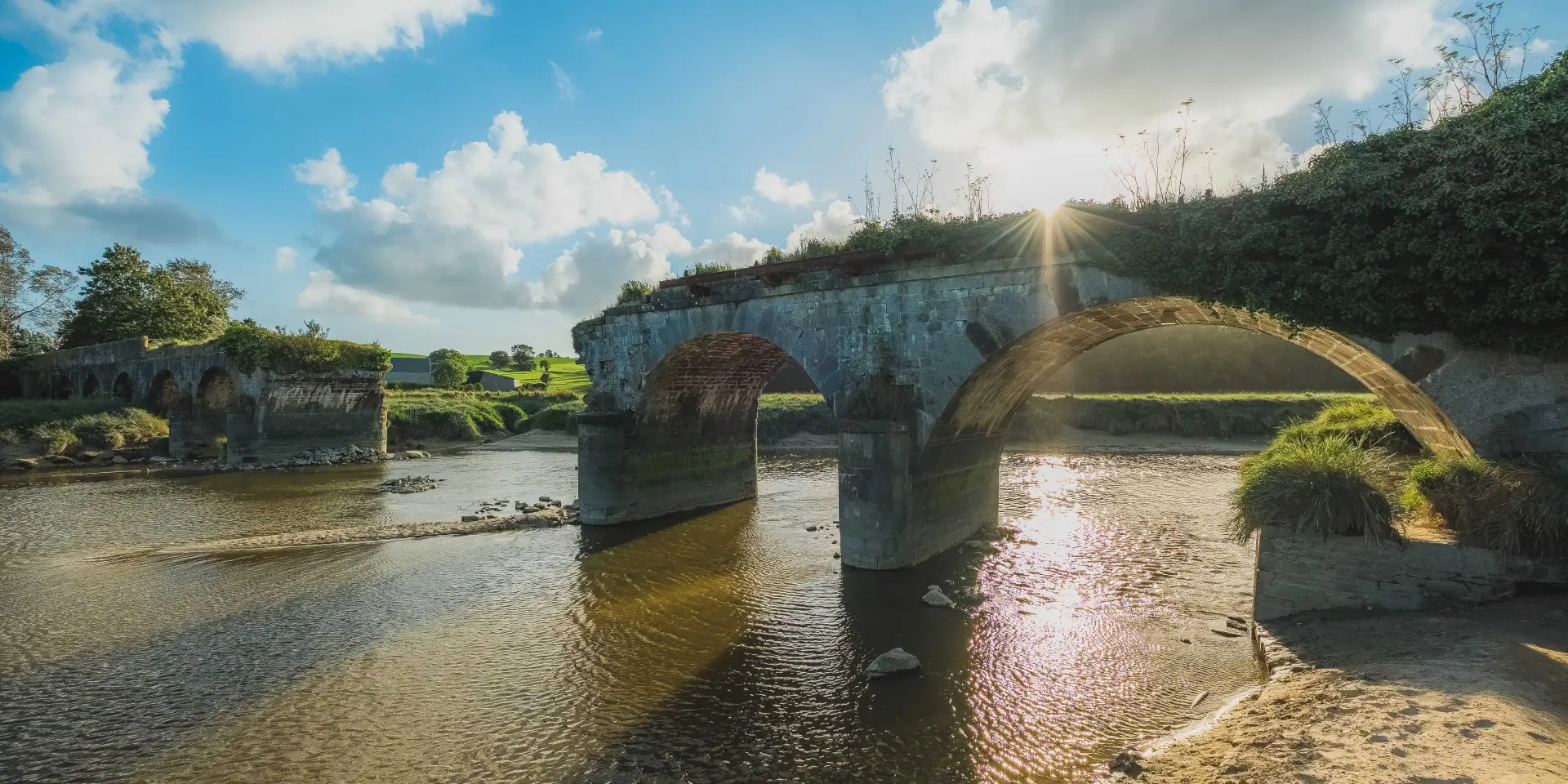 Steinbogenbrücke über einem Fluss mit umgebender Vegetation