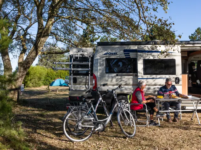 Deux personnes assises devant un camping-car avec des vélos à proximité
