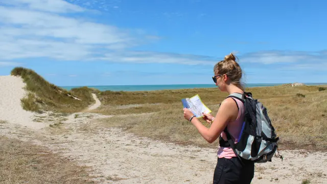 A woman hiking looks at a map outdoors