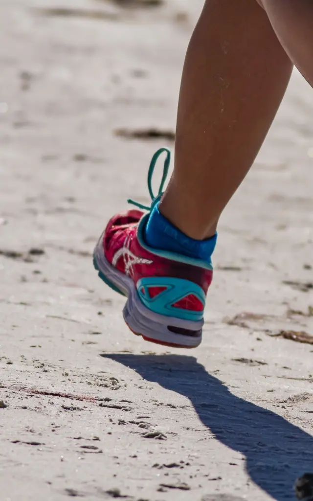 Pieds d'une personne courant sur la plage avec des chaussures de sport colorées