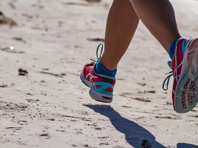 Pieds d'une personne courant sur la plage avec des chaussures de sport colorées