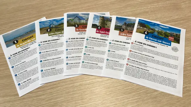 Sechs Touristenbroschüren auf Französisch auf einem Holztisch