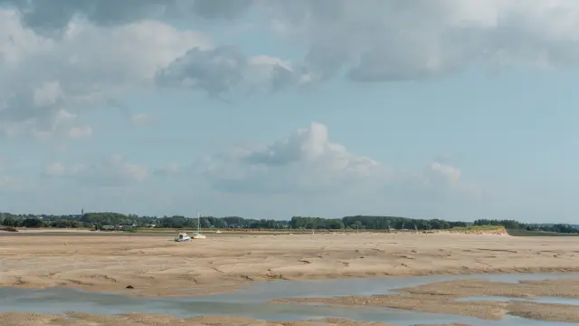 Sandy beach with water puddles and a cloudy sky