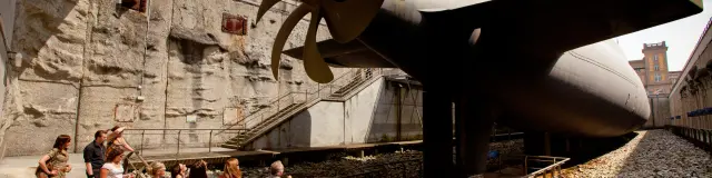 Group of people visiting a ship's propeller in a museum