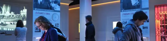 People examining objects in a museum with posters and blue ceiling lights