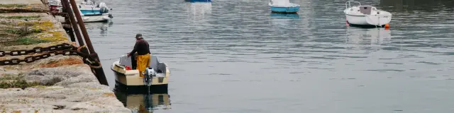 A fisherman in a yellow suit on a small boat