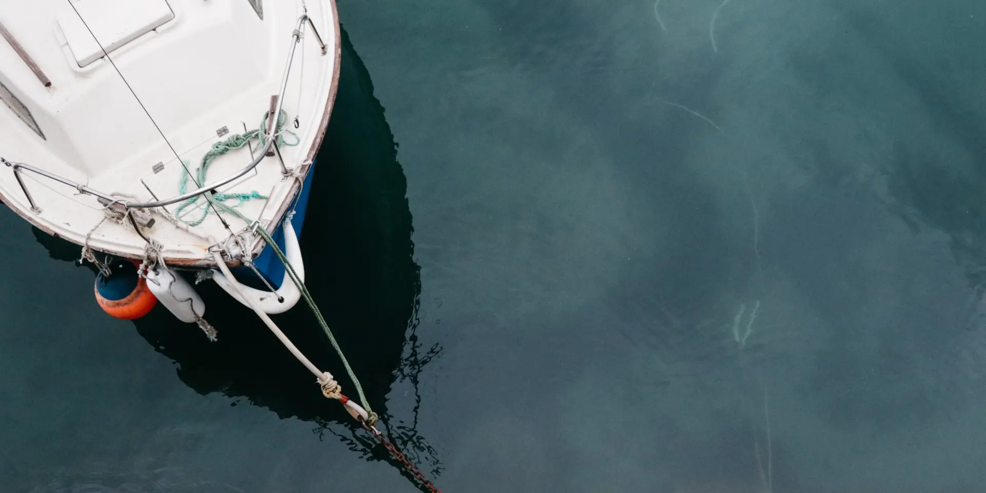 White boat moored to a stone dock with a rope