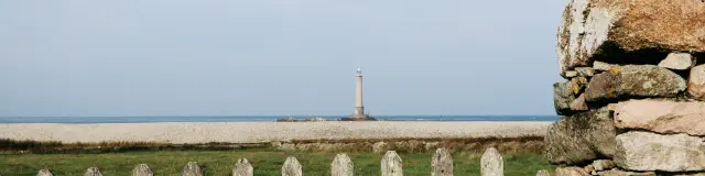 Ein Leuchtturm steht in der Ferne auf einem einsamen Strand