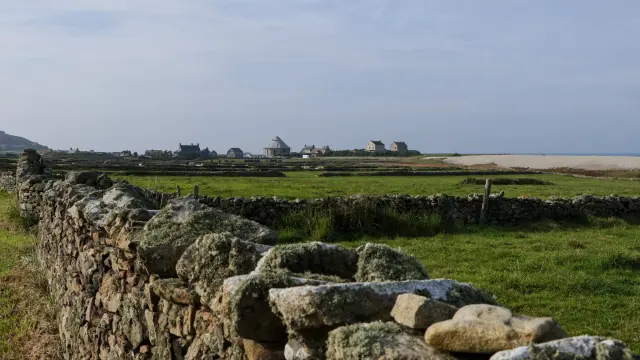 Steinmauer in einem grünen Feld mit Gebäuden in der Ferne