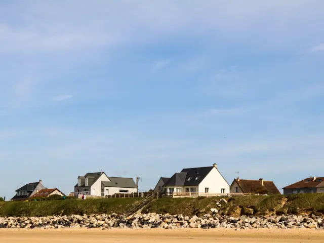 Häuser am sandigen Strand mit Felsen