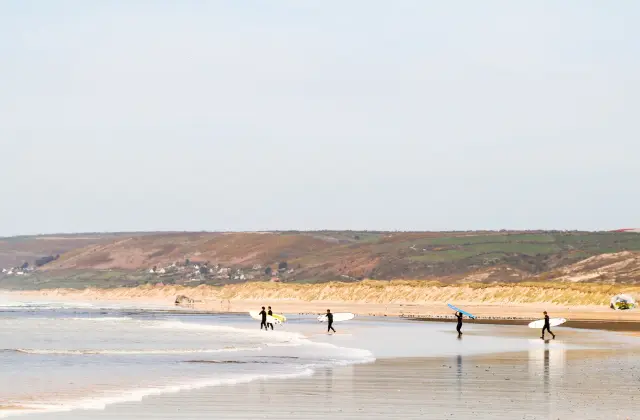 Mehrere Personen mit Surfboards gehen am Strand entlang
