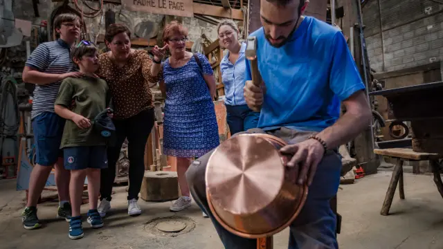A group of people watching a blacksmith working on metal