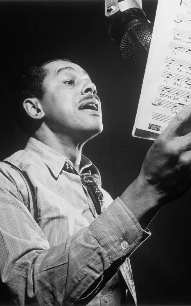 Un chanteur en train de lire une partition musicale devant un microphone