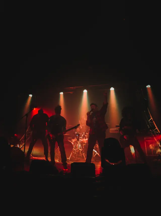 Groupe de musique jouant sur scène avec des projecteurs rouges