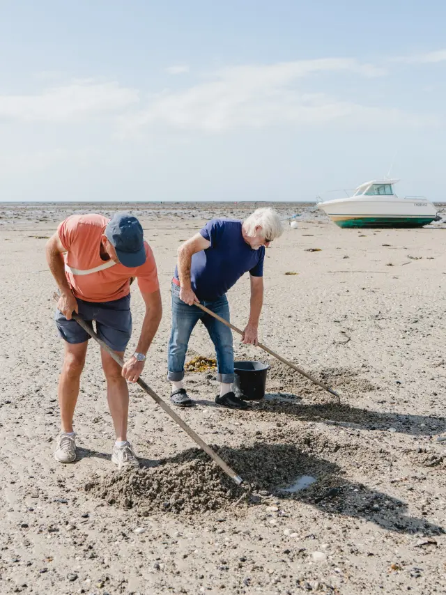 Zwei Personen sammeln Müll am Strand