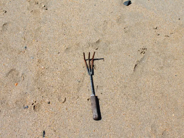 Rostige Heugabel am Strand verlassen