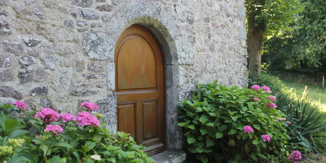 Wooden door in a stone wall with pink flowers
