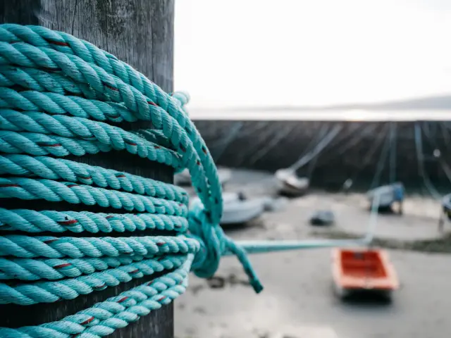 Close-up of a blue rope coiled around a post on a dock