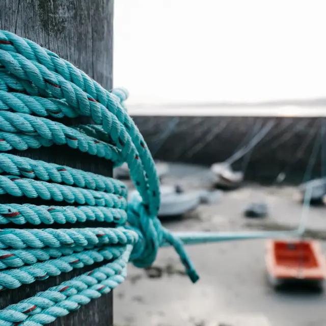 Close-up of a blue rope coiled around a post on a dock