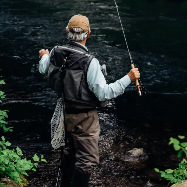 Un homme pêche dans une rivière avec une canne à pêche
