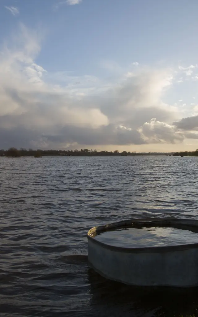 Sonnenuntergang über einem Gewässer mit einem schwimmenden Objekt im Vordergrund