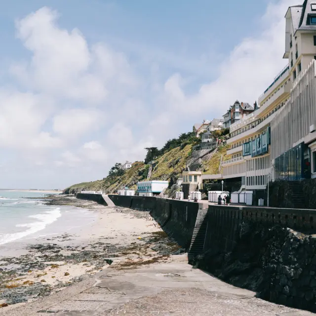 Coastal walkway with white buildings and a sandy beach