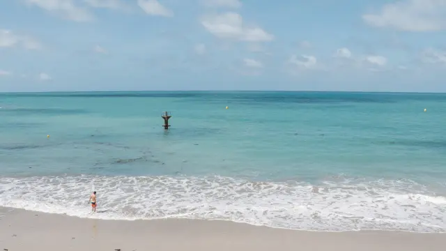 Two people on a fine sandy beach with a turquoise sea