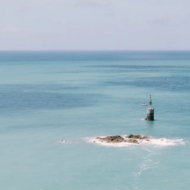 Phare sur une petite île rocheuse au milieu de la mer turquoise à Granville