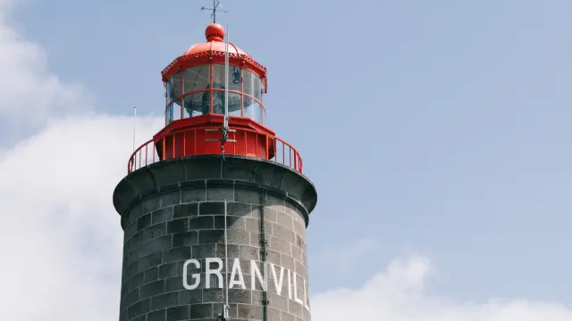 Phare de Granville avec une lanterne rouge et un ciel bleu