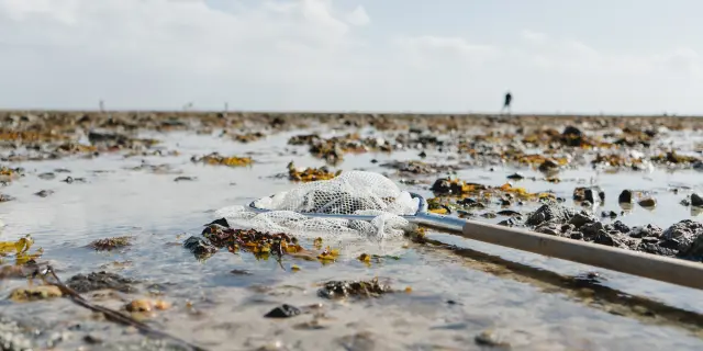 Abfall und verlassenes Fischernetz am Strand