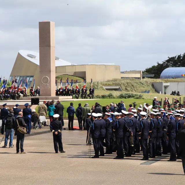 Military ceremony with soldiers in uniform and a monument in the background
