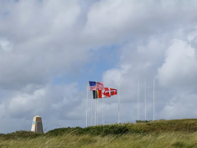 Trois drapeaux flottant avec un ciel nuageux en arrière-plan