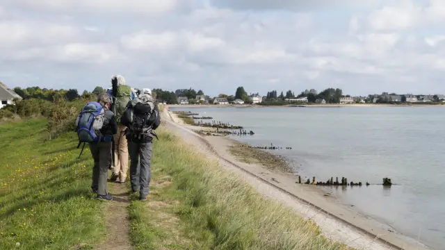 Drei Wanderer mit Rucksäcken, die eine Karte betrachten