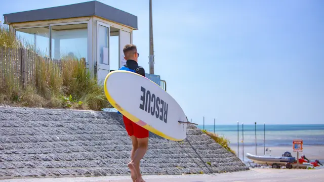 A surfer carrying a surfboard with the text 'BREIZH'