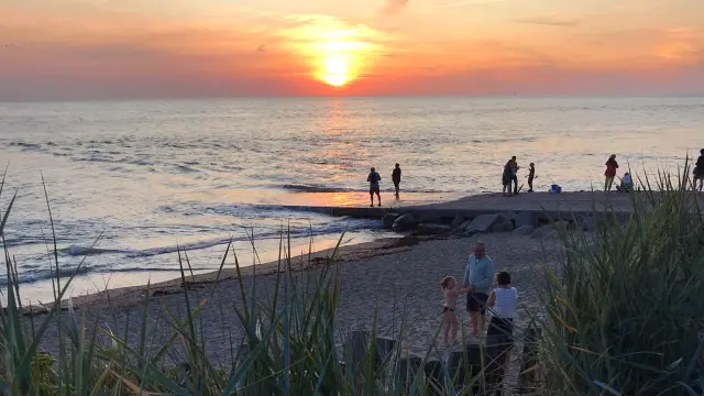Groupe de personnes marchant sur une plage au coucher du soleil à Blainville sur Mer