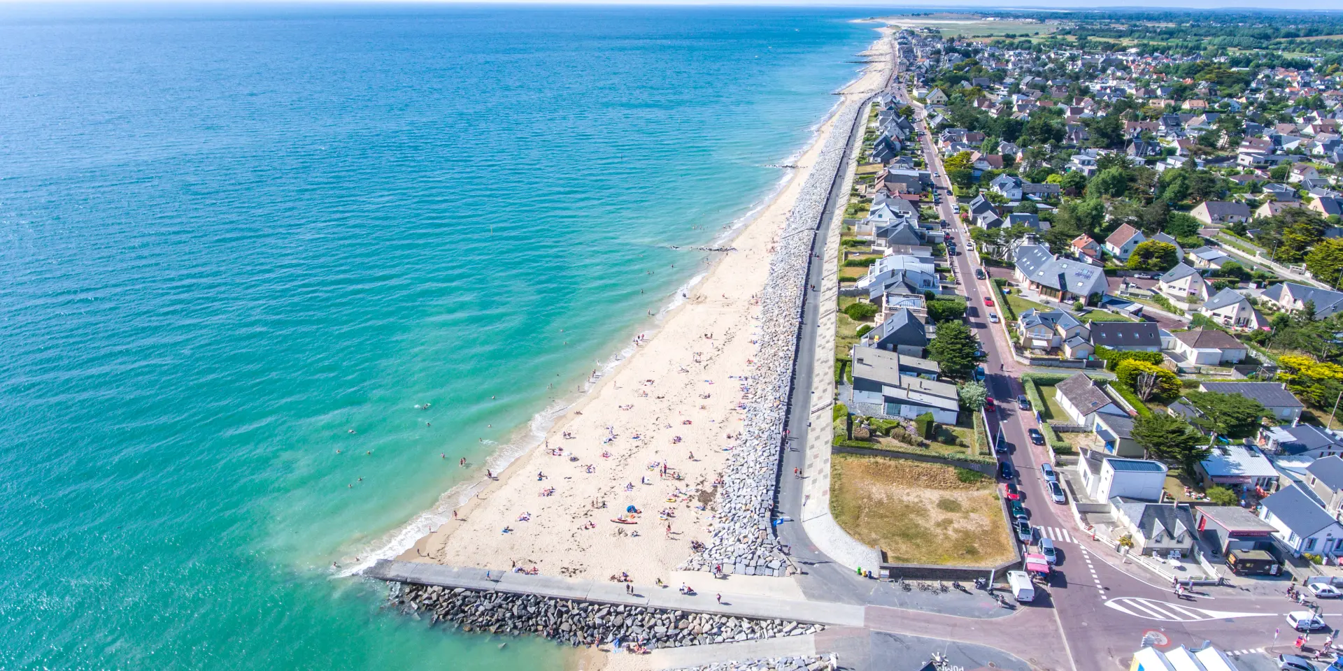 Aerial view of a fine sandy beach bordered by houses and a road
