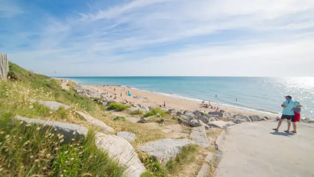 Two people walking on a beach path with a view of the sea