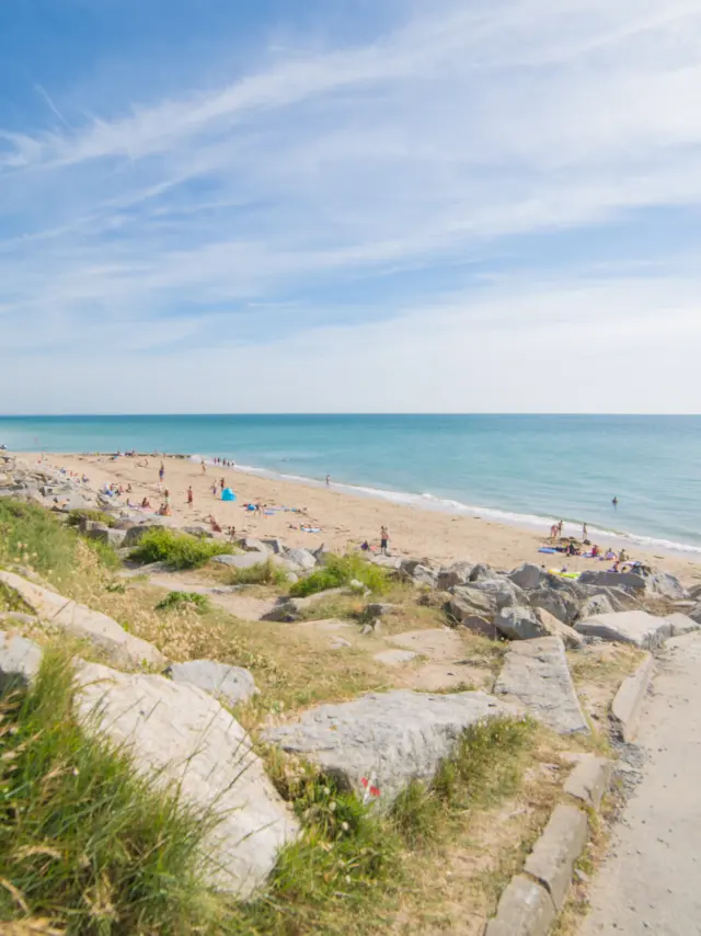Zwei Personen gehen auf einem Strandweg mit Meerblick