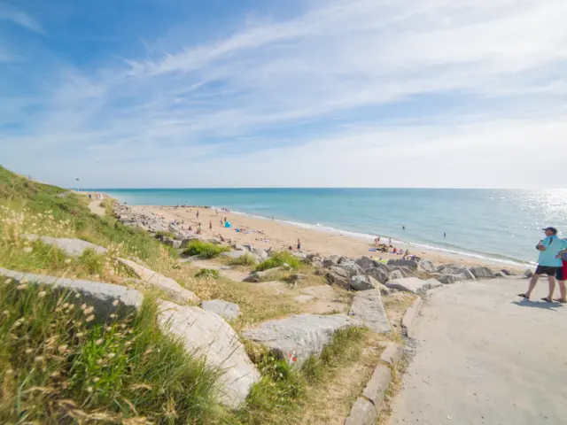 Zwei Personen gehen auf einem Strandweg mit Meerblick