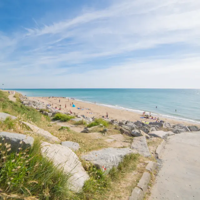 Deux personnes marchent sur un chemin de plage avec vue sur la mer